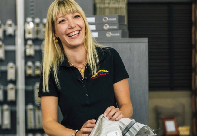 Lachende Frau die Gardinenmuster auf dem Tisch liegen hat 