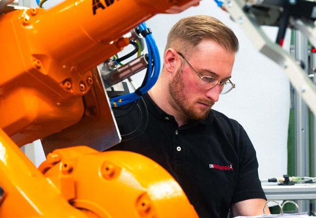 Mann steht neben einer Maschine und hält einen Ordner in seiner Hand